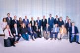 2024 Global Board of Directors pose together in front of a white curtain.